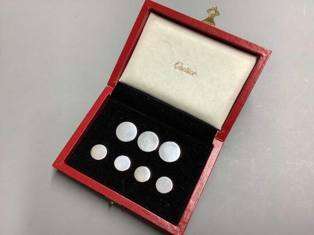 A cased set of seven sterling white metal buttons (two sizes), five bearing the stamp 'Cartier', largest diameter 19mm